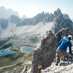 People with climbing gear are descending from the Toblinger Knoten summit, in the Background is the tre cime di lavaredo, Italy
