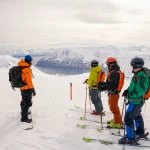 skiers overlooking snowy mountains scaled