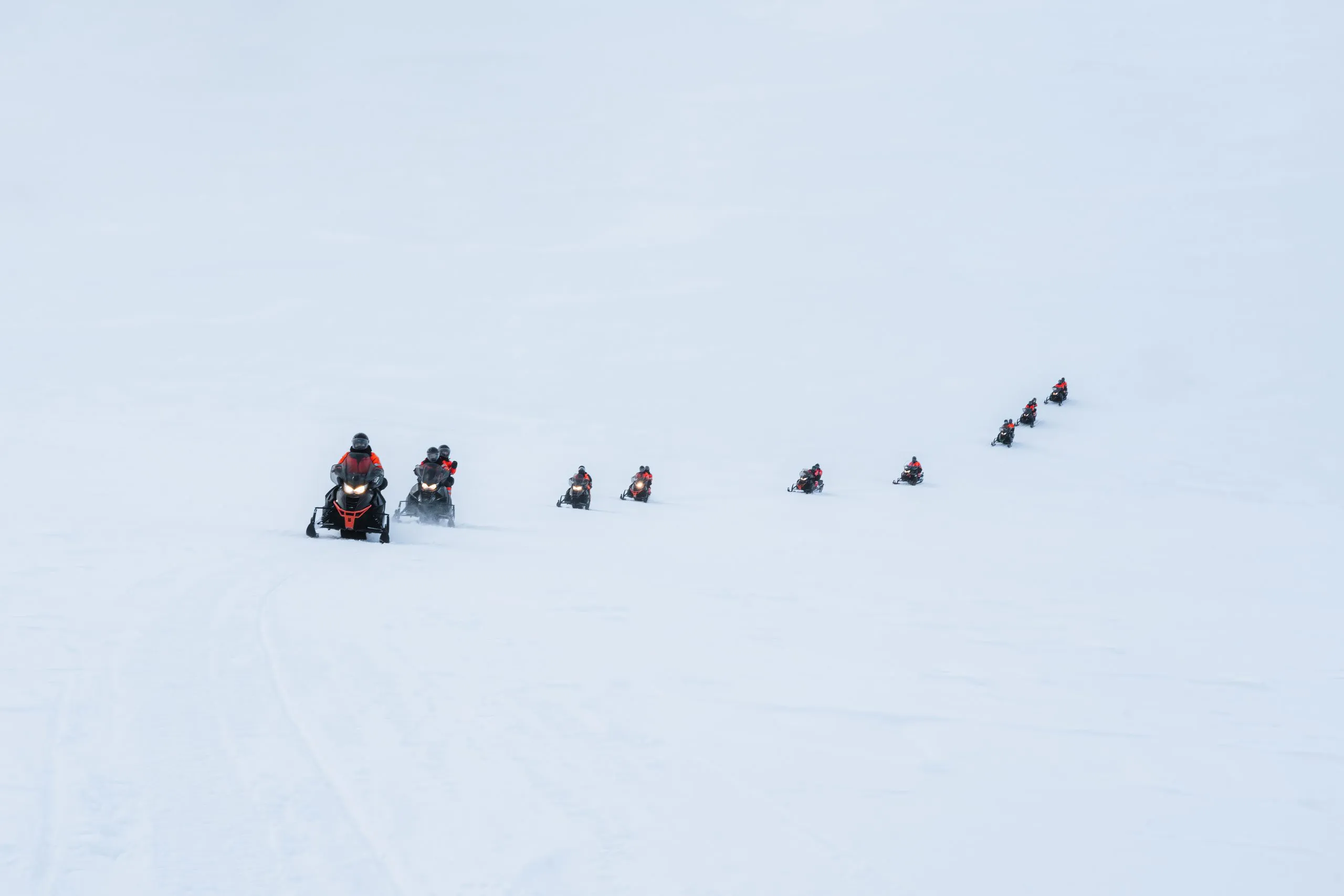 Group of tourists riding snowmobiles on snowy glacier mountain